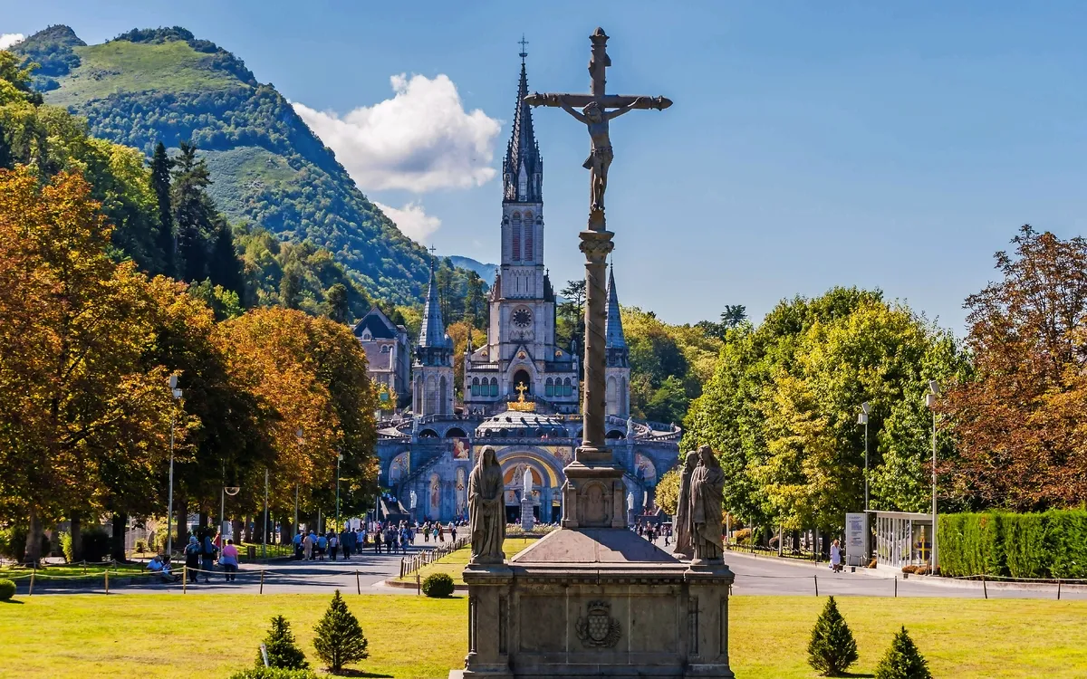 Eine Basilika in Lourdes, Frankreich, umgeben von Bergen und Bäumen.