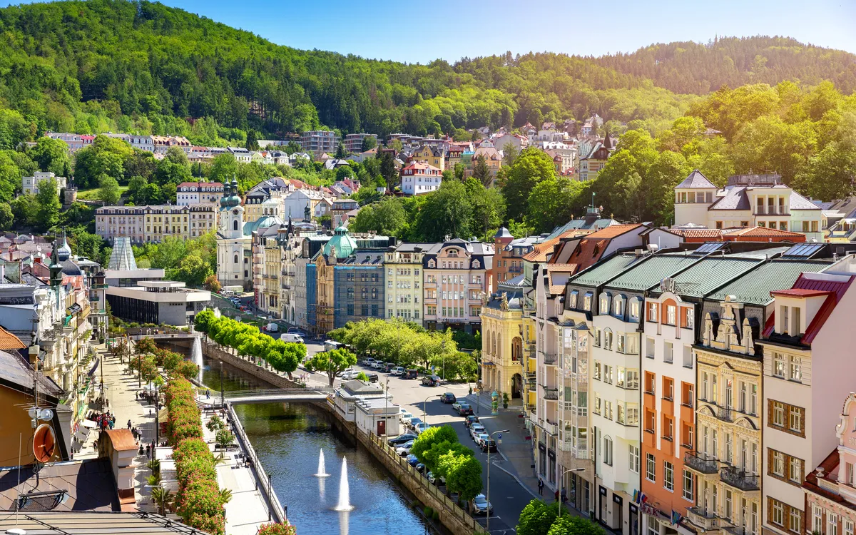 Stadtansicht von Karlovy Vary mit Fluss und grüner Hügellandschaft im Hintergrund
