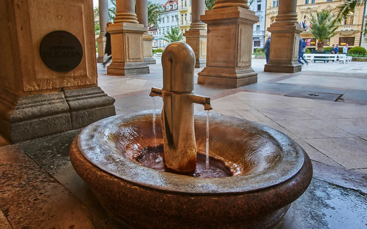 Brunnen mit fließendem Wasser in einer überdachten Passage.