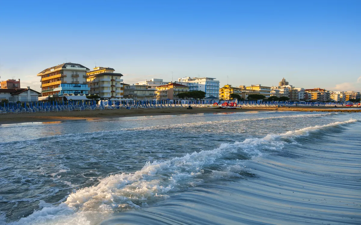 Strandpromenade mit Gebäuden und ruhiger Meeresküste bei klarem Himmel.
