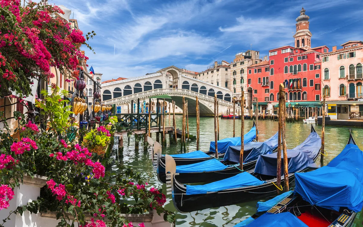 Venedig: Riala-Brücke, bunte Gebäude und Gondeln am Kanal.