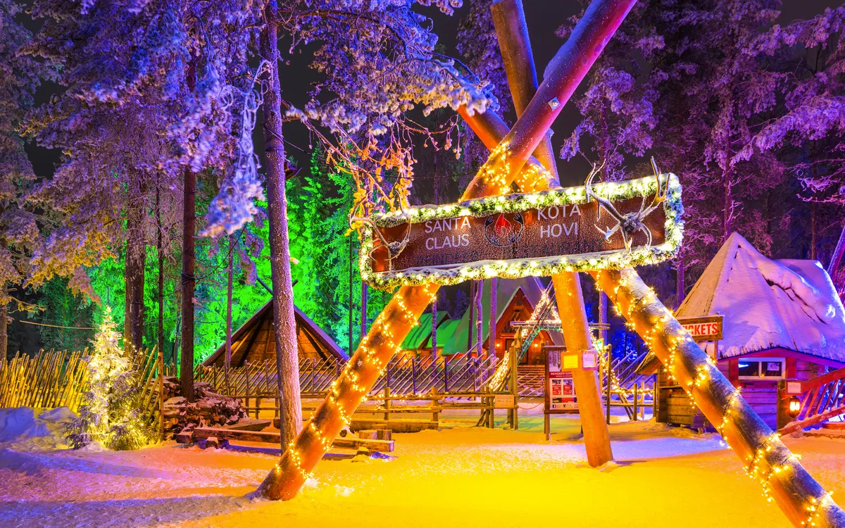 Beleuchtete Schneeszene mit Zelt und Holzschild in winterlichem Wald.