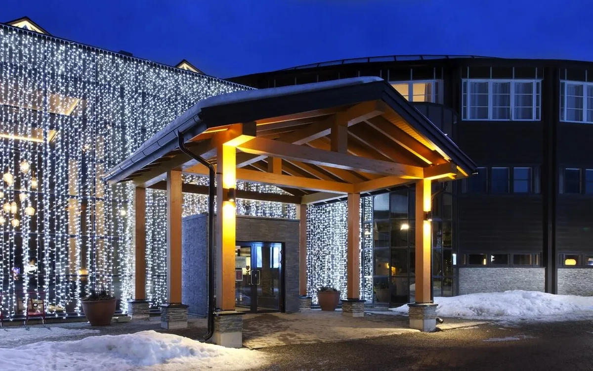 Eingangsbereich eines Hotels im Schnee bei Abenddämmerung.