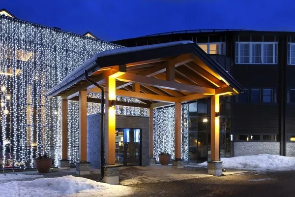 Eingangsbereich eines Hotels im Schnee bei Abenddämmerung.