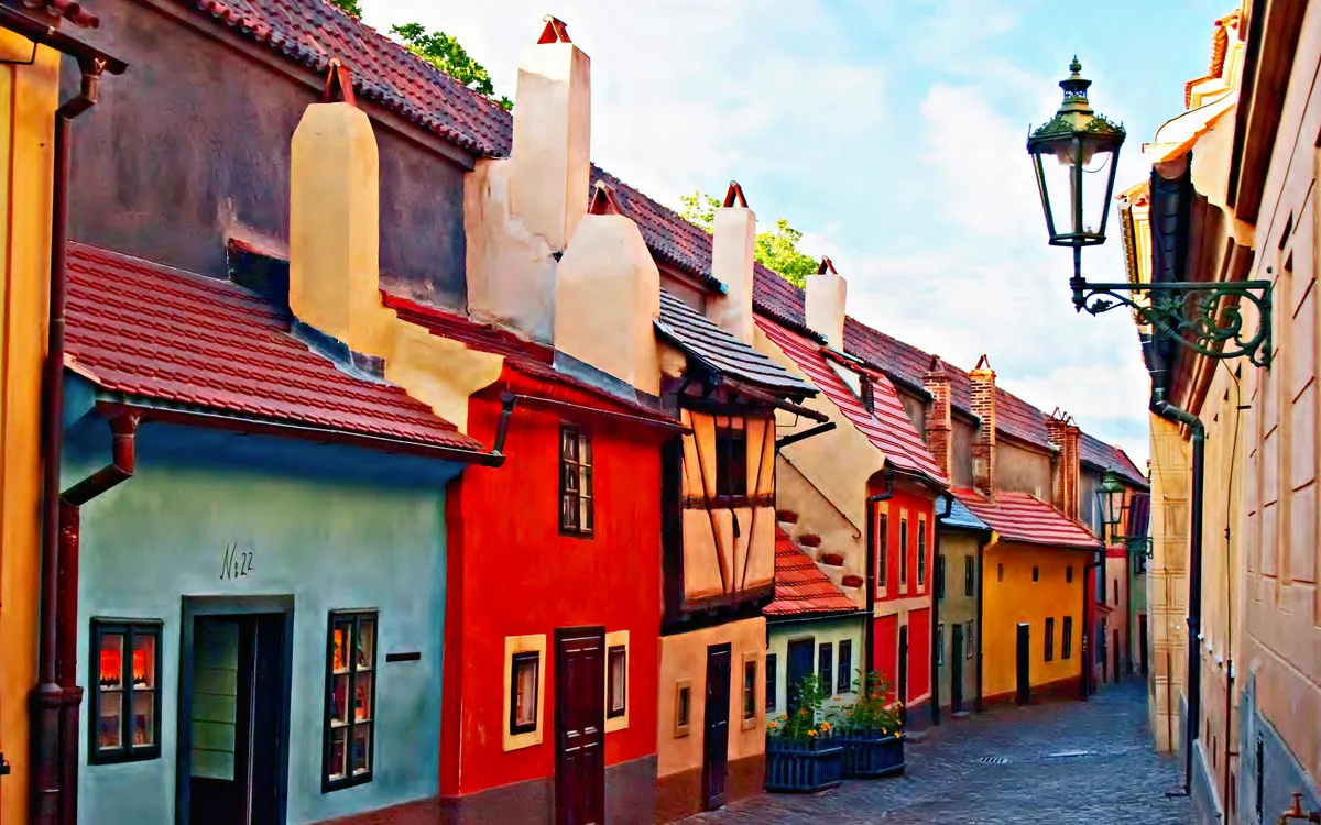 Bunte historische Häuser in einer schmalen, kopfsteingepflasterten Straße mit Laterne.