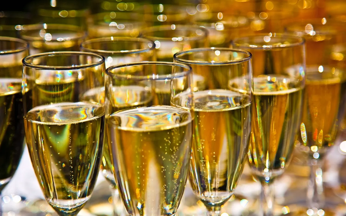 Mehrere Gläser mit Champagner gefüllt, im Hintergrund unscharf.