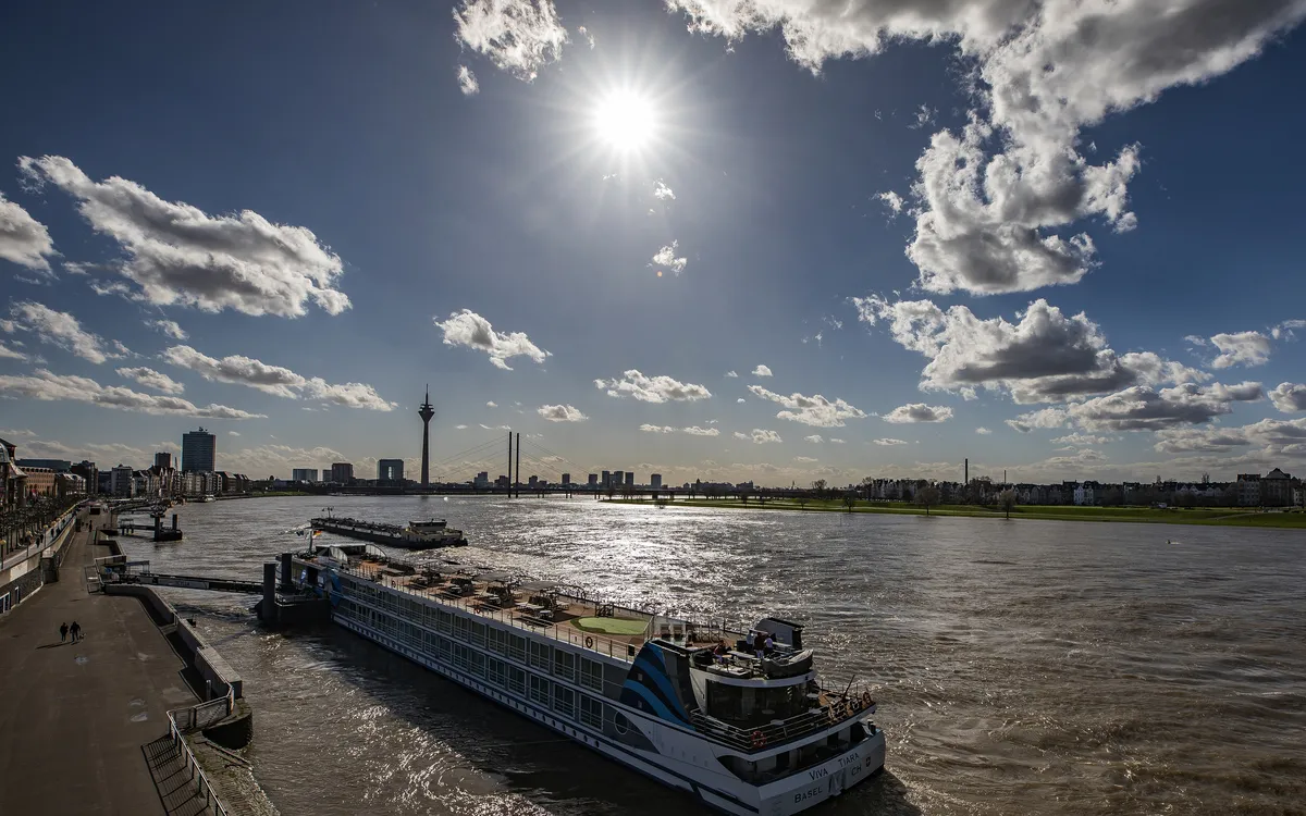 Kreuzfahrtschiff auf dem Rhein bei Sonnenschein, Düsseldorf im Hintergrund.