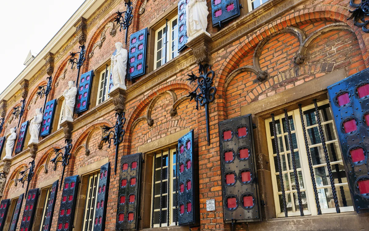 Fassade eines historischen Backsteingebäudes mit dekorativen Fensterläden.