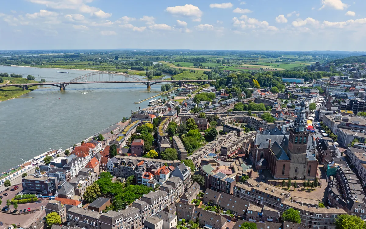 Luftaufnahme einer Stadt mit Flussufer und Brücke bei klarem Himmel.