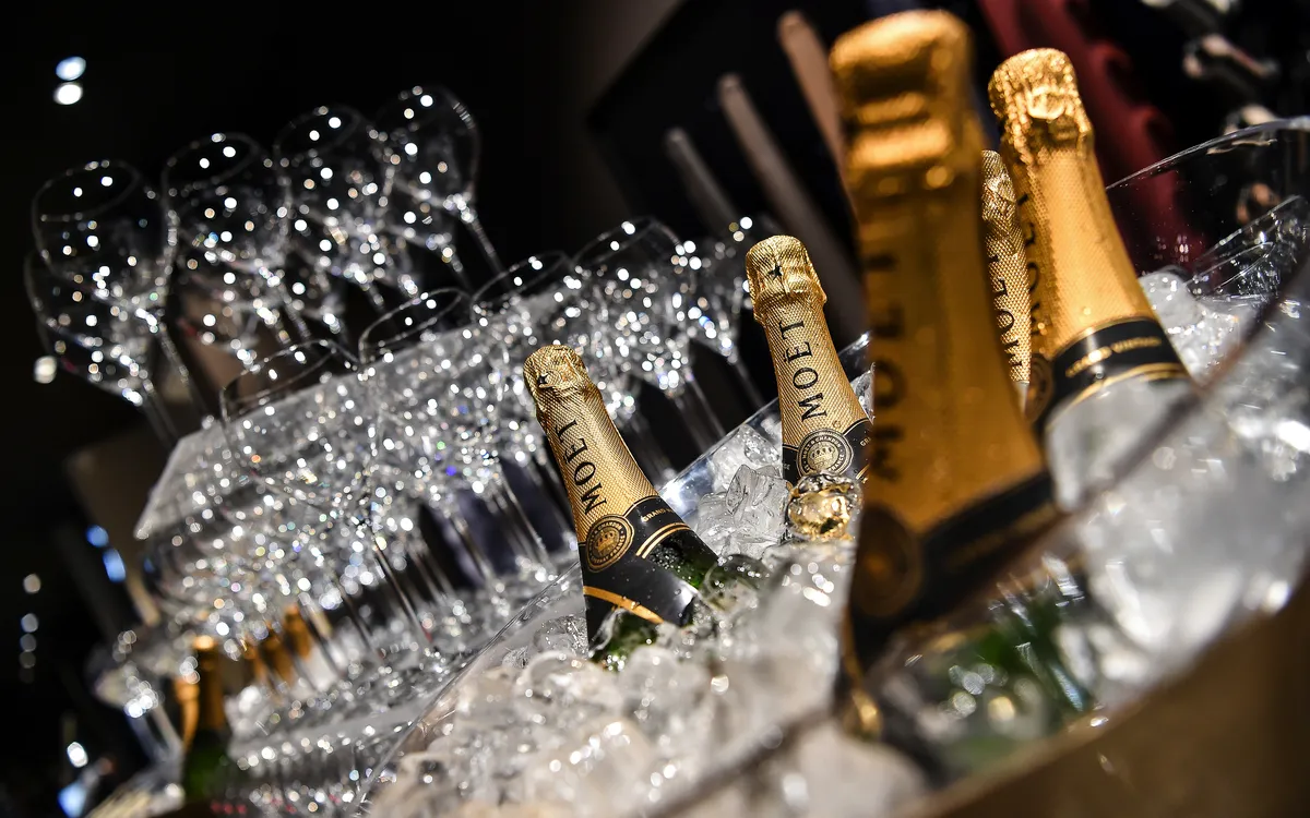 Champagnerflaschen in Eis mit leeren Gläsern im Hintergrund.