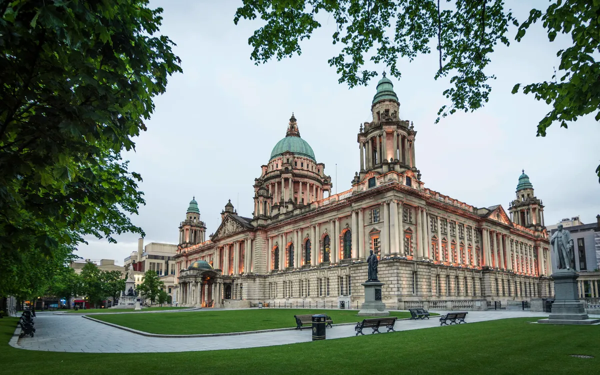 Historisches Gebäude mit grüner Kuppel in einer Parklandschaft.