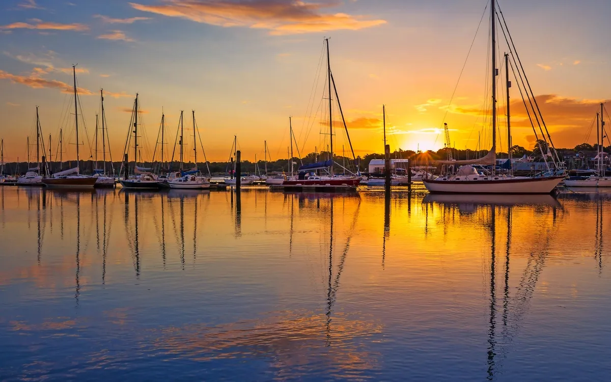 Segelboote im Hafen bei Sonnenuntergang mit Spiegelung im Wasser