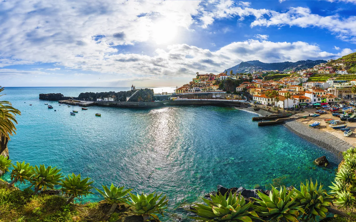 Fischerort Câmara de Lobos auf Madeira, umgeben von blauem Meer und grünen Hügeln.