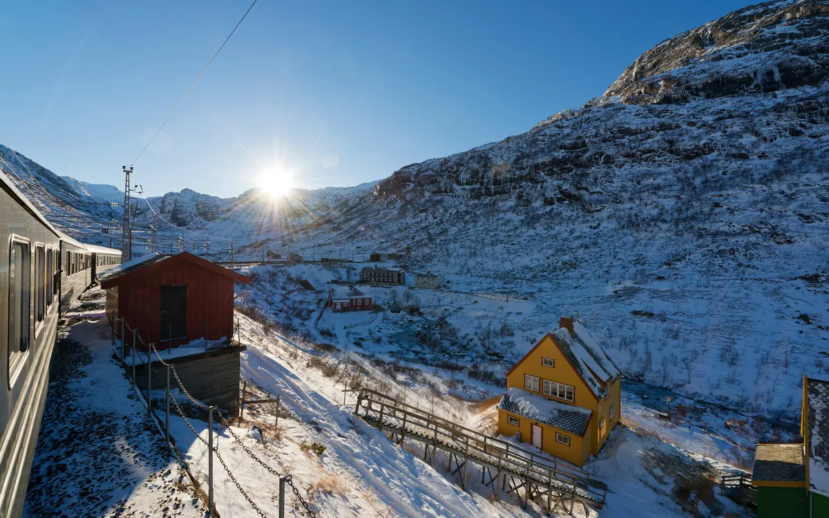 Flåmsbana im Schnee mit Bergen im Hintergrund bei Sonnenschein, Norwegen.