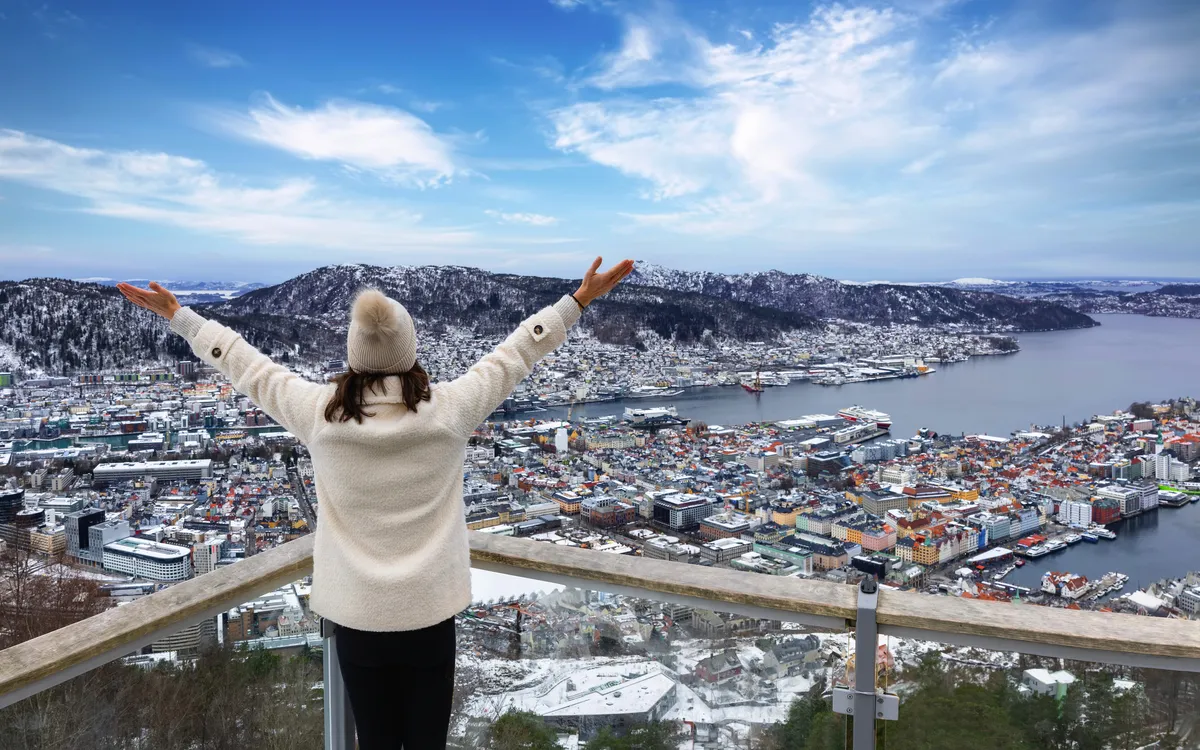 Frau genießt Blick auf Bergen im Winter von Aussichtsplattform in Norwegen.