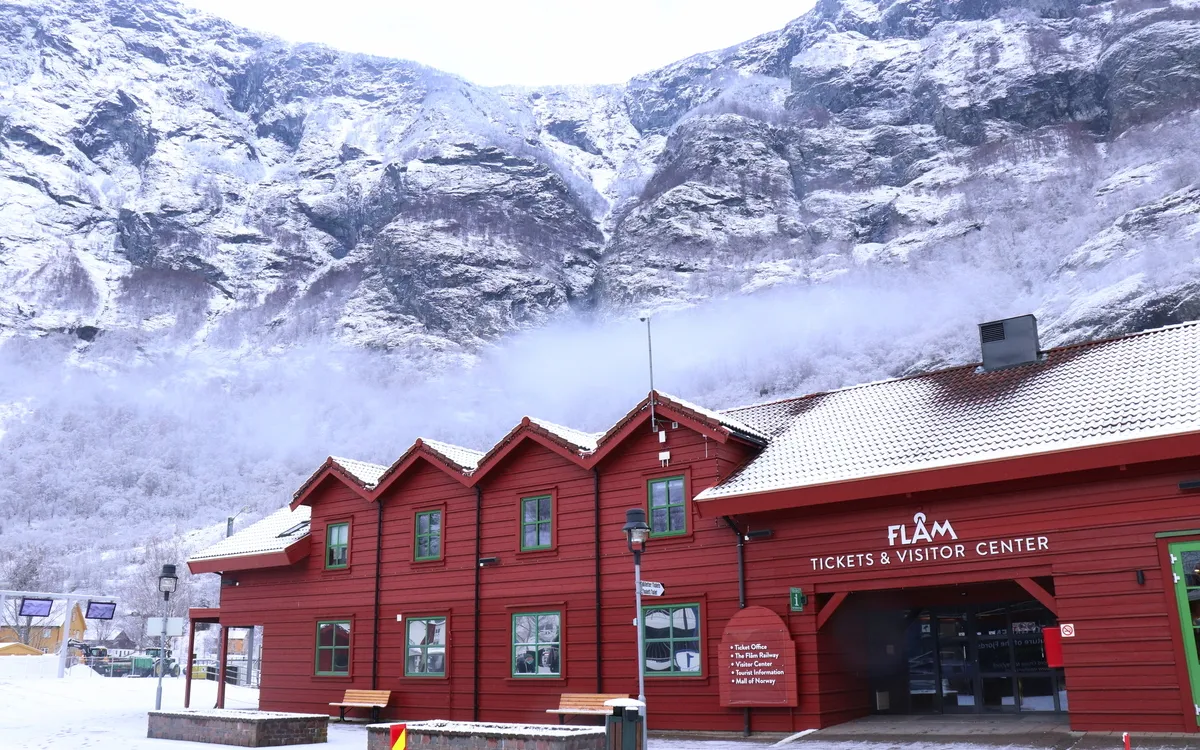Besucherzentrum in Flåm vor schneebedeckten Bergen im Winter.