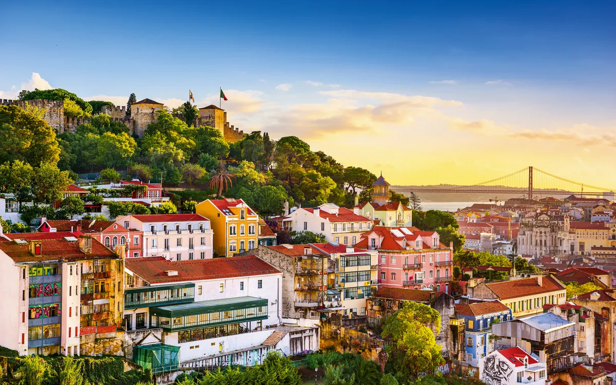 Blick auf Lissabon mit bunten Häusern und Burg bei Sonnenuntergang.