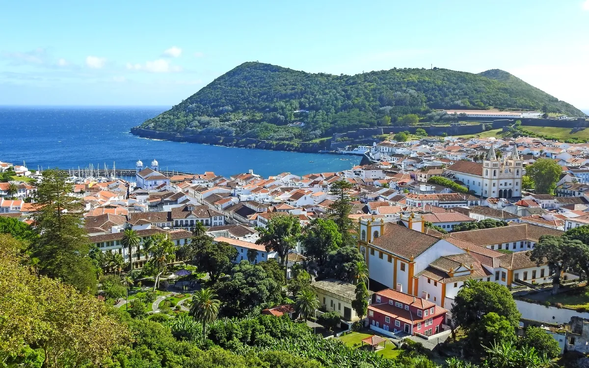 Stadt am Meer mit grüner Landschaft und Hügel im Hintergrund.