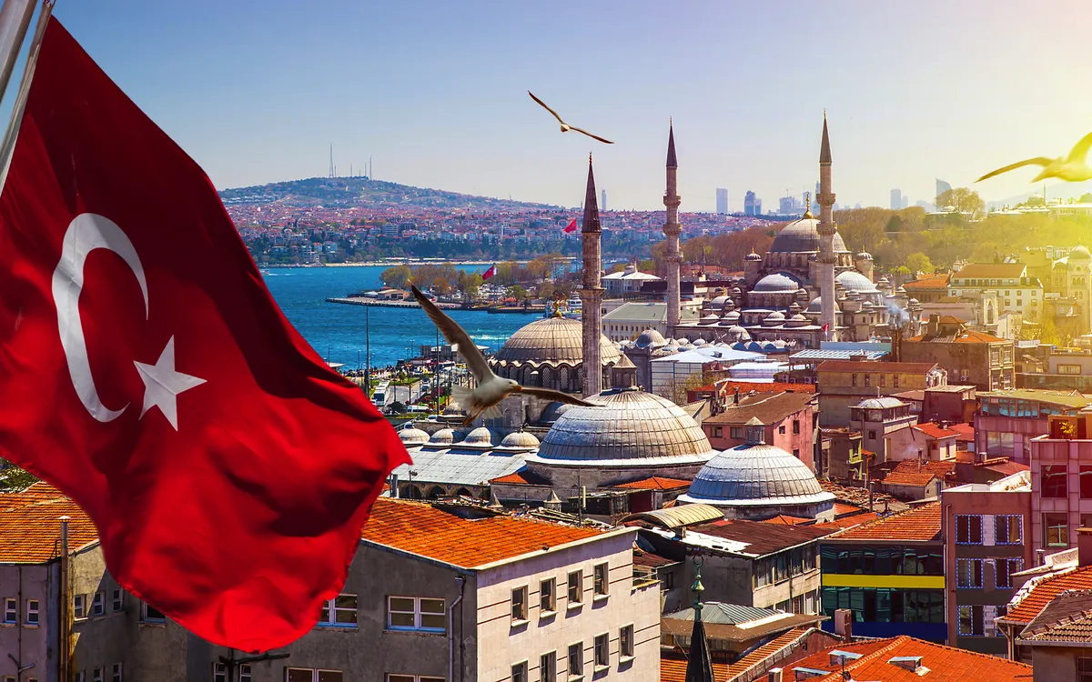 Türkische Flagge weht über der Skyline von Istanbul mit Moscheen und Vögeln im Hintergrund.