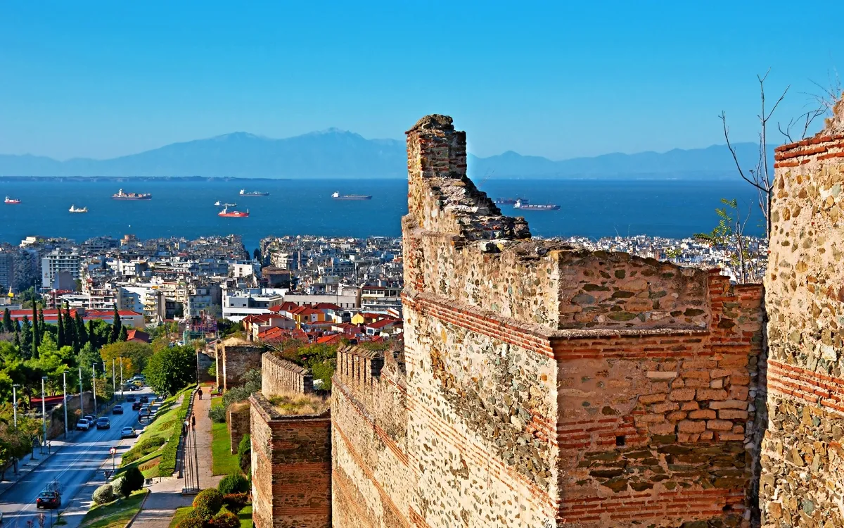 Blick auf Thessaloniki mit Stadtmauern, Meer und Schiffen im Hintergrund.