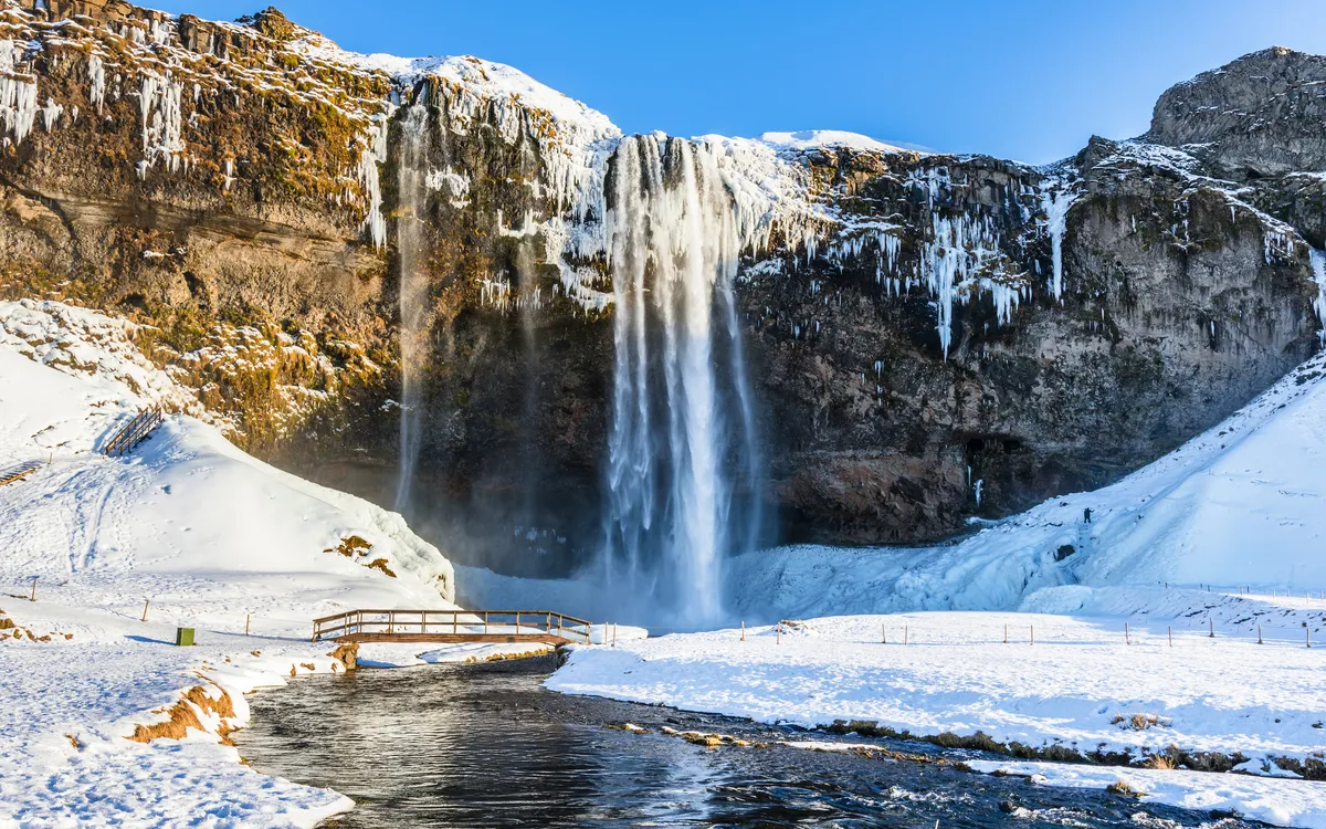 Wasserfall im Winter mit Schnee und gefrorenen Bereichen im Sonnenschein