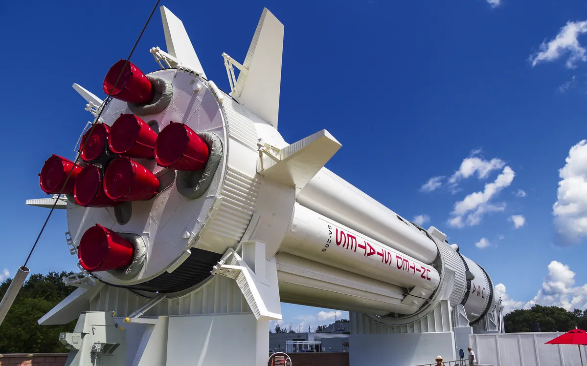 Große weiße Rakete mit roten Triebwerken an einem sonnigen Tag.