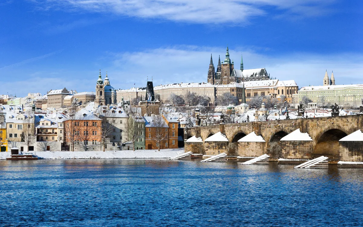 Schneebedeckte Prager Burg mit Blick auf die Karlsbrücke und die Moldau.