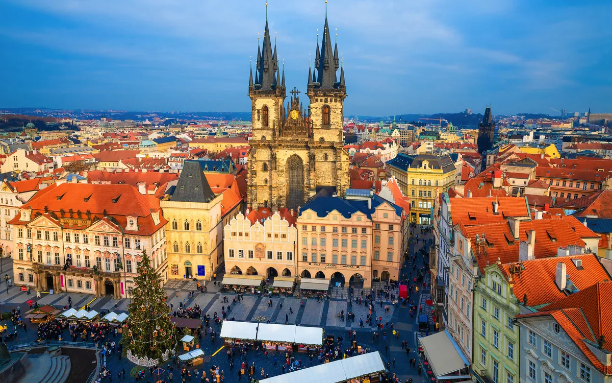 Historischer Platz mit gotischer Kirche und Menschenmengen in einer Stadt.