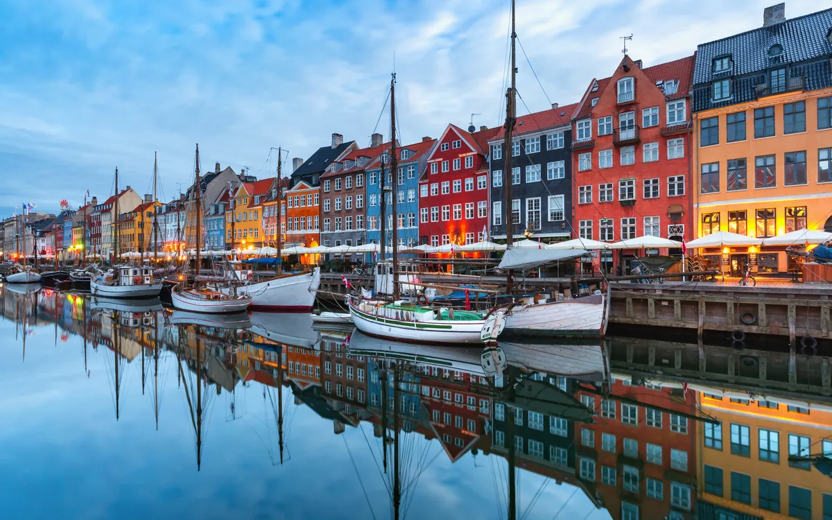 Bunte Gebäude und Boote an einem Kanal bei Abenddämmerung.