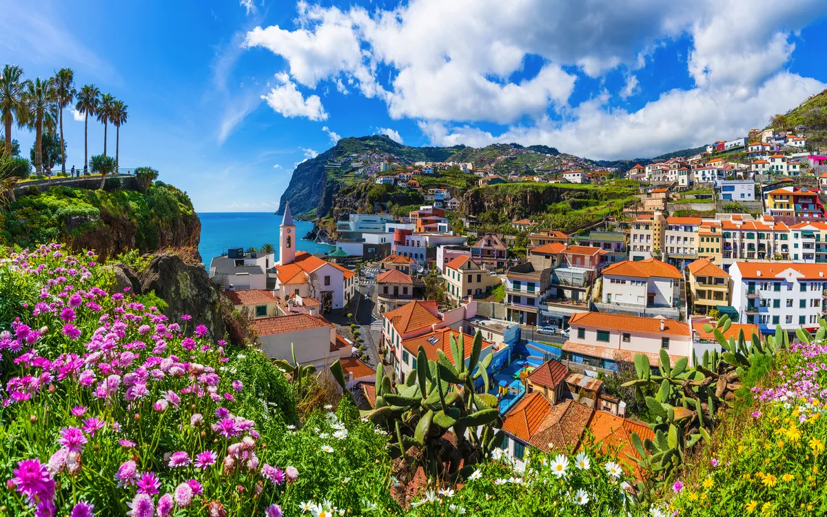 Blick auf den Fischerort Câmara de Lobos auf Madeira mit bunten Häusern und Atlantikküste.