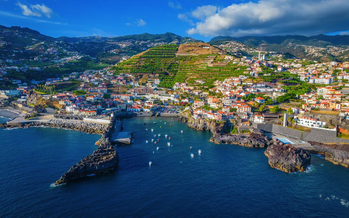 Luftaufnahme von Câmara de Lobos auf Madeira mit Hafen und umliegenden Hügeln.