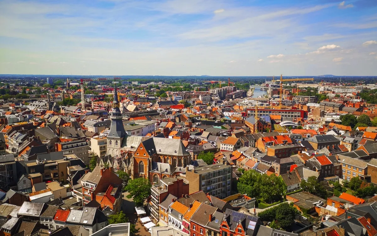 Blick auf eine europäische Stadt mit vielen roten Ziegeldächern und einer Kirche.
