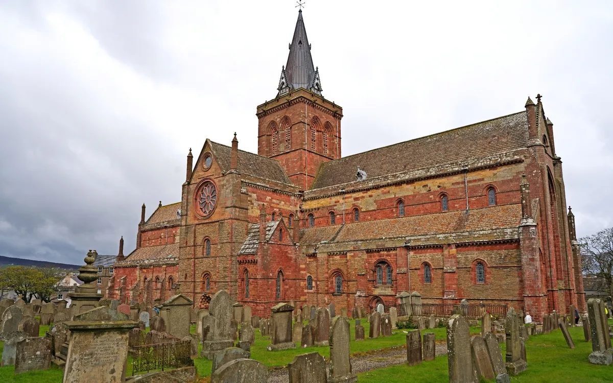 Backsteinkirche mit Kirchturm auf einem Friedhof.