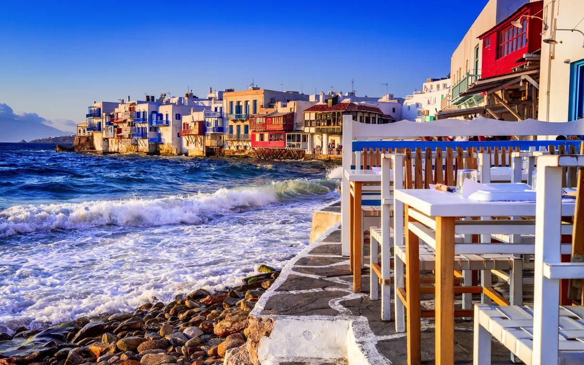 Tische am Meer vor der bunten Küste von Mykonos