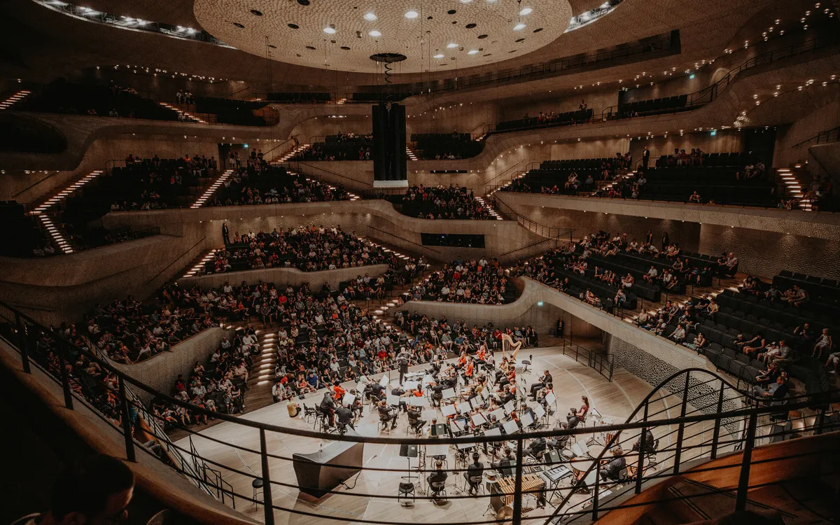 Innenansicht der Elbphilharmonie in Hamburg mit Orchester und Publikum.
