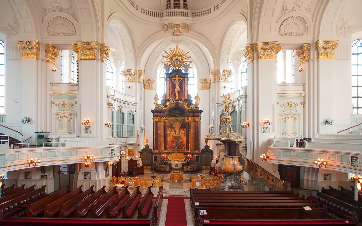 Innenraum einer prächtigen Barockkirche mit Altar und Kirchenbänken.