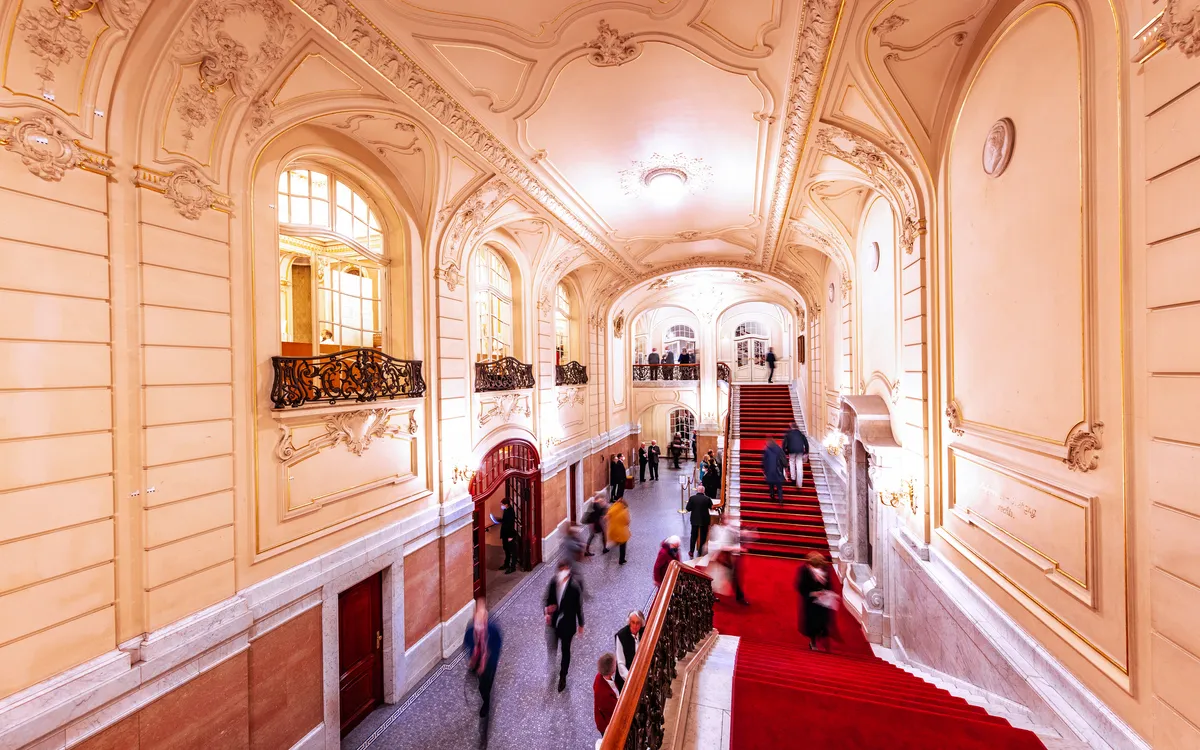 Besucher in der Eingangshalle der Laeiszhalle mit prächtigen Verzierungen und rotem Teppich