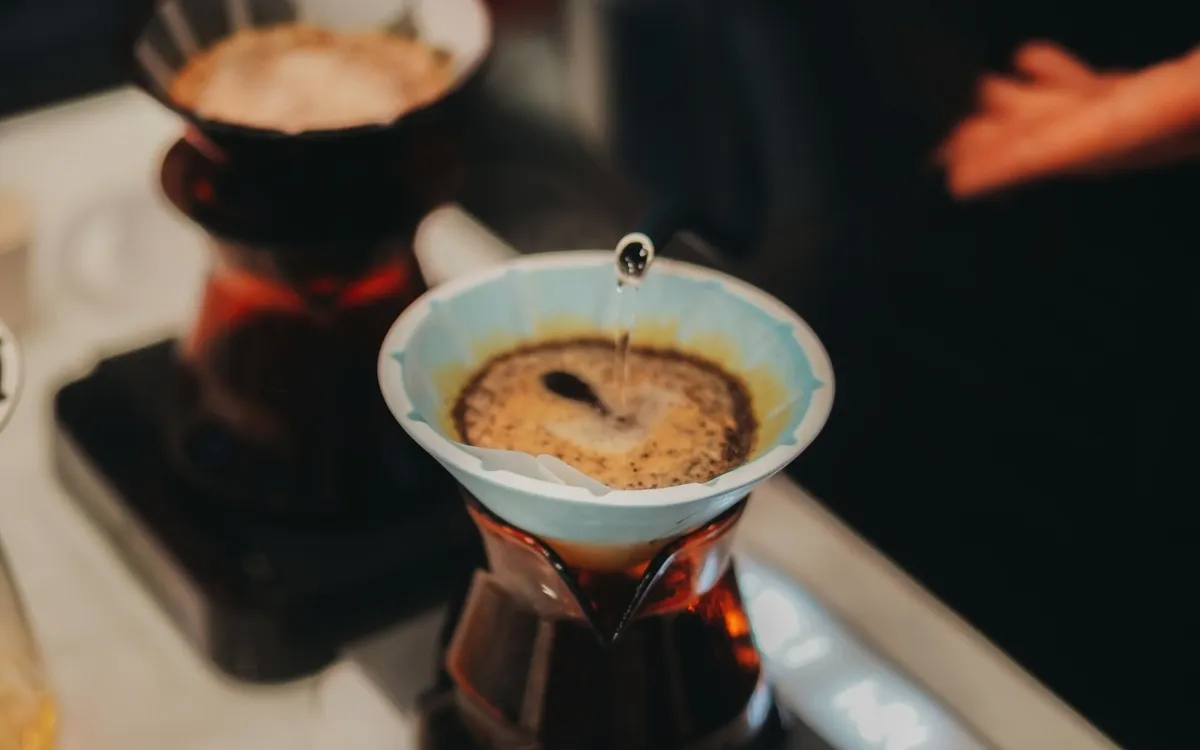 Barista gießt heißes Wasser in einen Kaffeefilter für frisch gebrühten Kaffee.