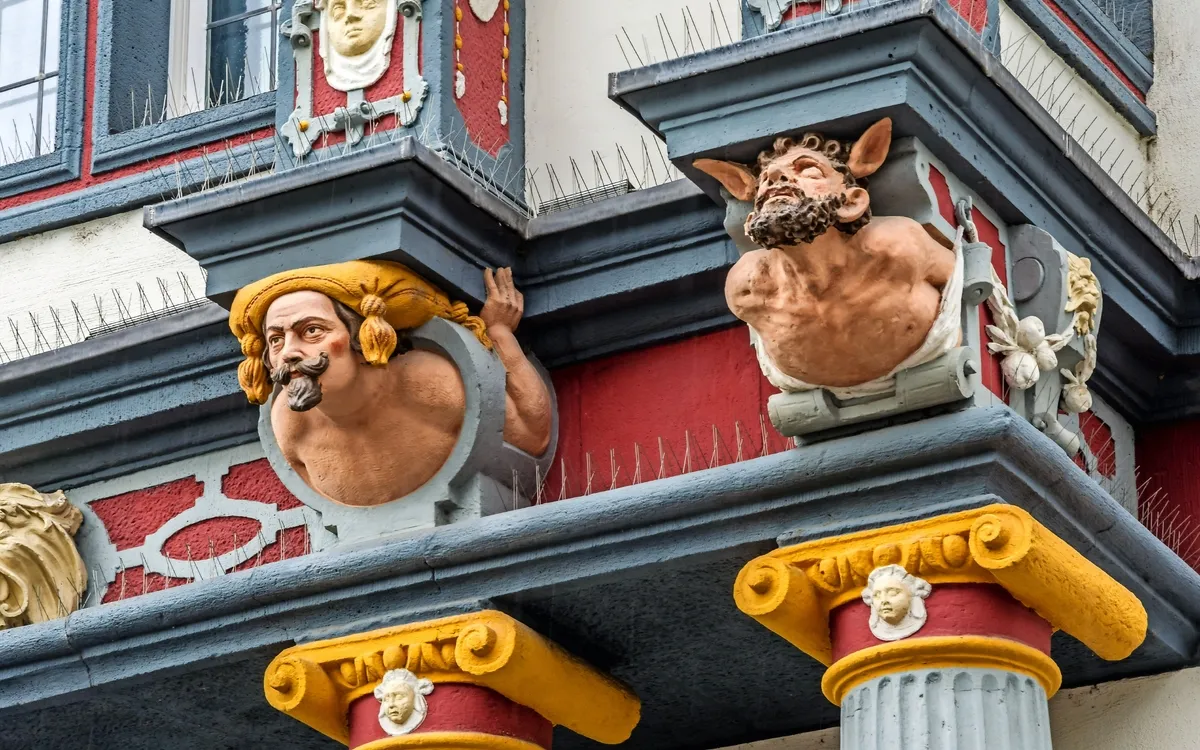 Verzierter Erker mit kunstvollen Reliefs und Büsten an einem historischen Gebäude.