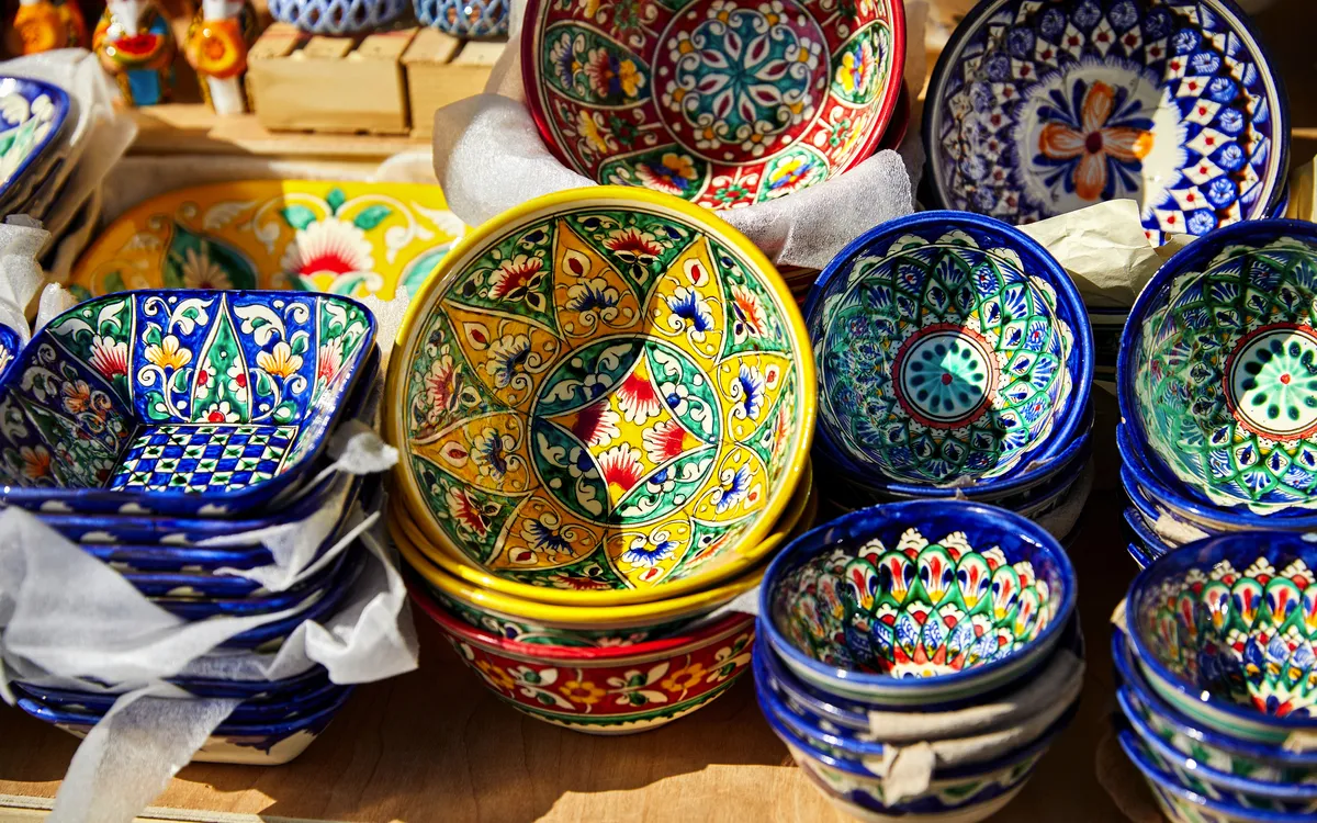 Verschiedene bunte handbemalte Keramikschalen, gestapelt und ausgestellt auf einem Markt.